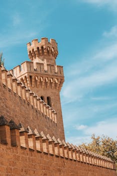 Historic stone fort tower under a bright blue sky in Mallorca.