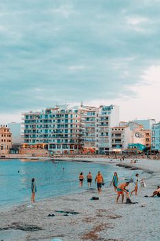 Serene beach scene in Palma de Mallorca with people enjoying the evening shoreline