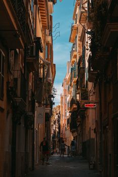 A beautiful narrow street in Palma de Mallorca with vibrant buildings and pedestrians strolling.