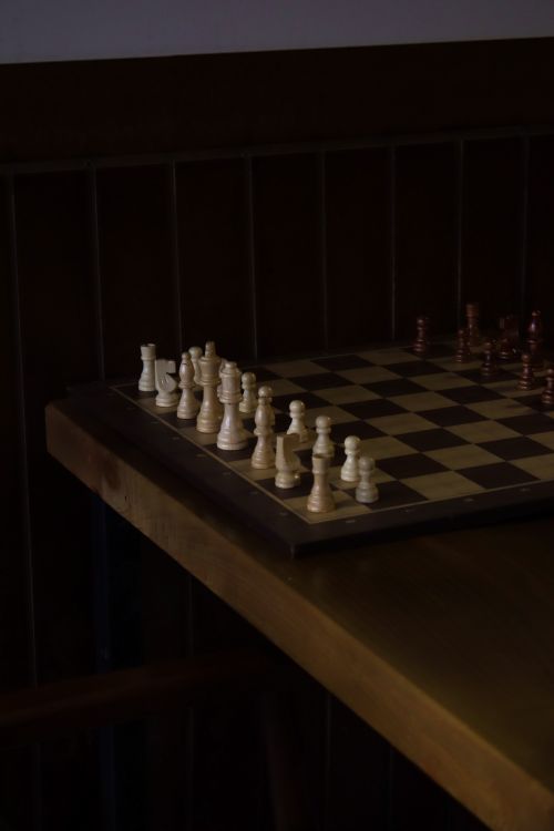 Free A dark, vintage-style photo of a wooden chessboard with chess pieces, offering a classic game mood. Stock Photo