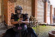 A woman dressed as Catrina with artistic makeup sits outdoors in Mexico City.