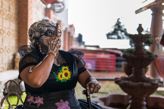 Elderly woman with artistic makeup celebrates Day of the Dead in Mexico City, showcasing vibrant costume and cultural traditions.