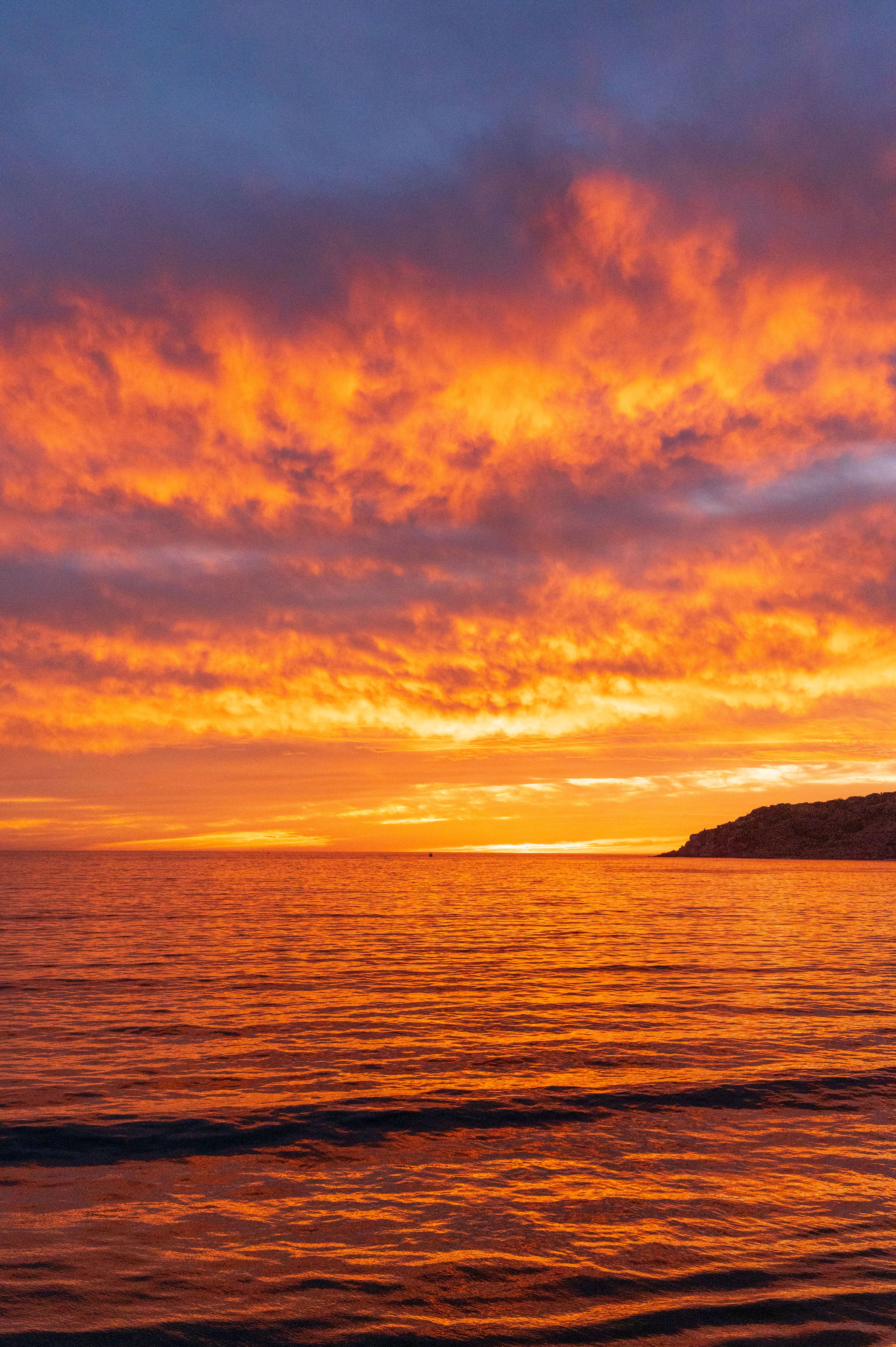 Fotomural Impresionante atardecer sobre la playa de Mazatlán con cielos vibrantes en naranja y azul reflejándose en el océano.