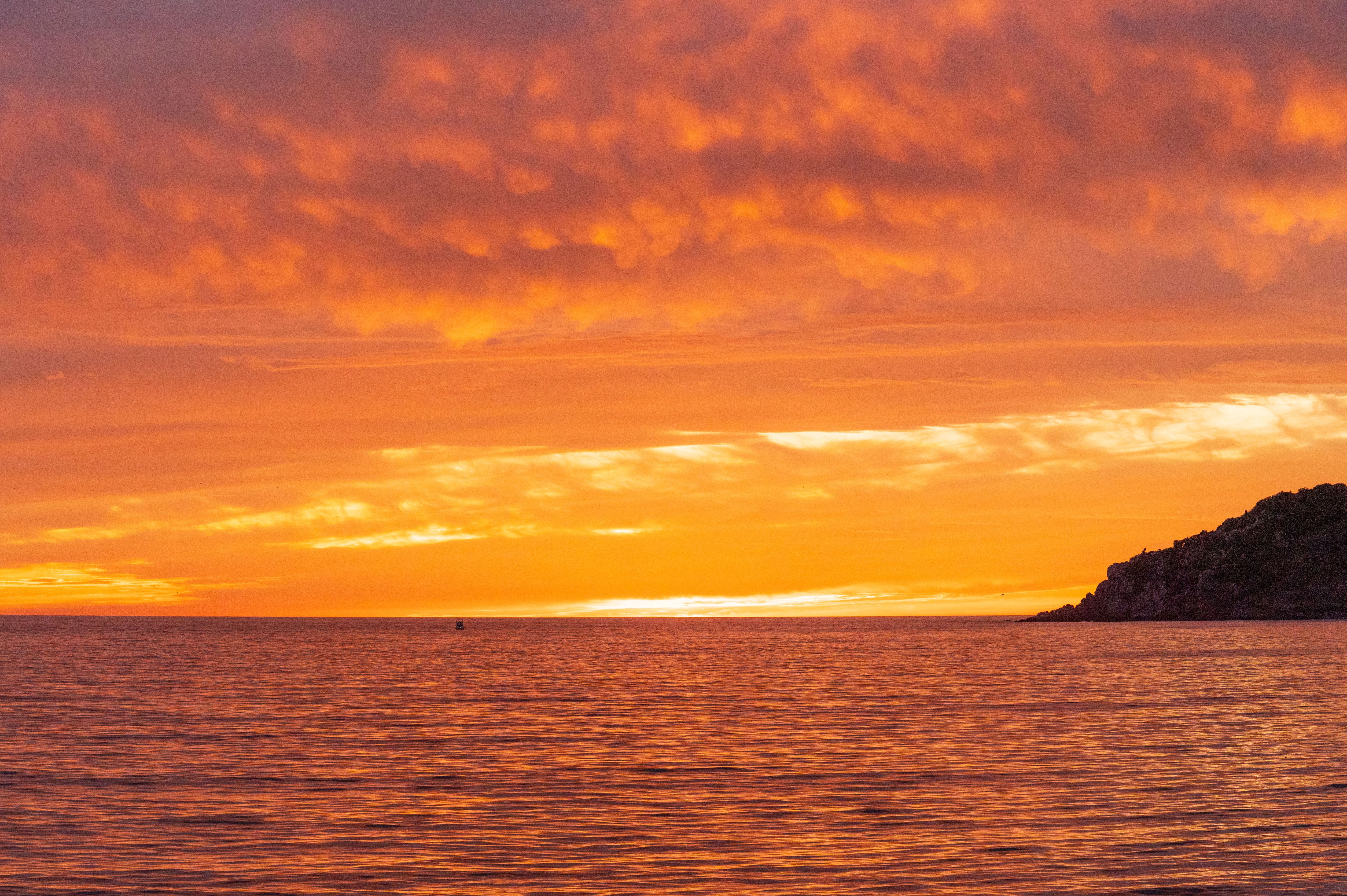 A sunset over the ocean with clouds and boats · Free Stock Photo