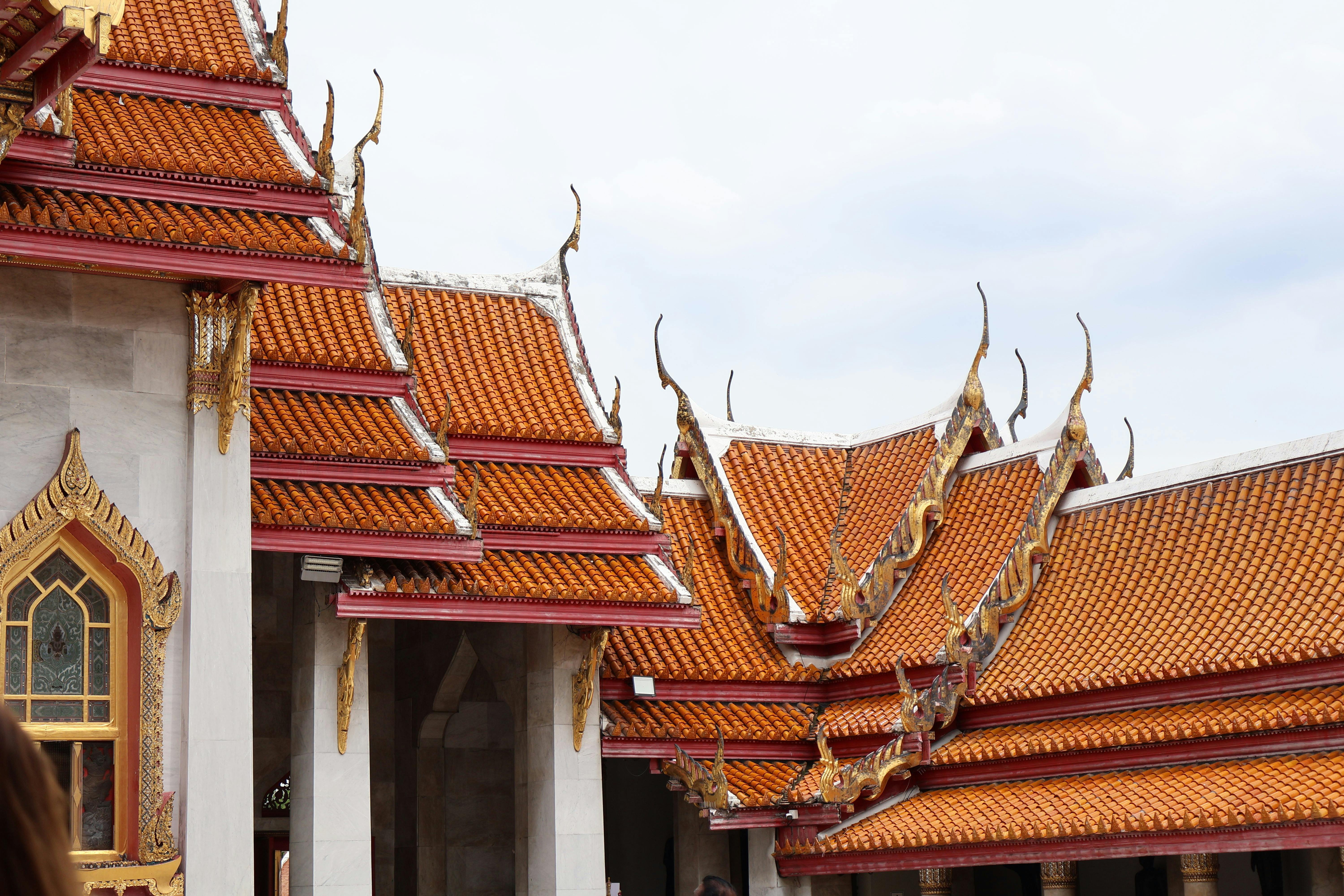 Detailed view of traditional Thai temple roofs with intricate designs under a bright sky.