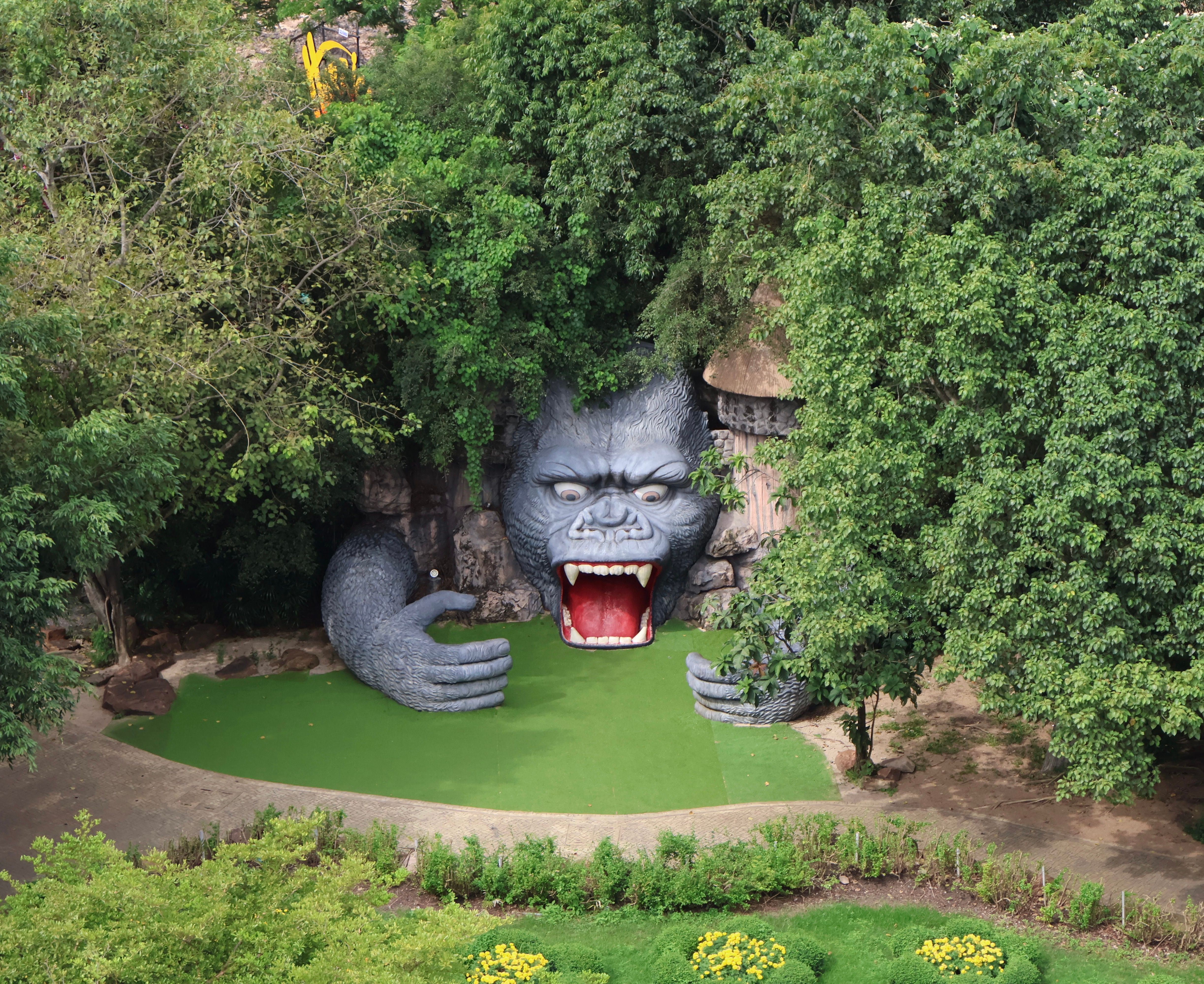 Giant gorilla statue emerging from lush greenery, creating a dramatic scene.