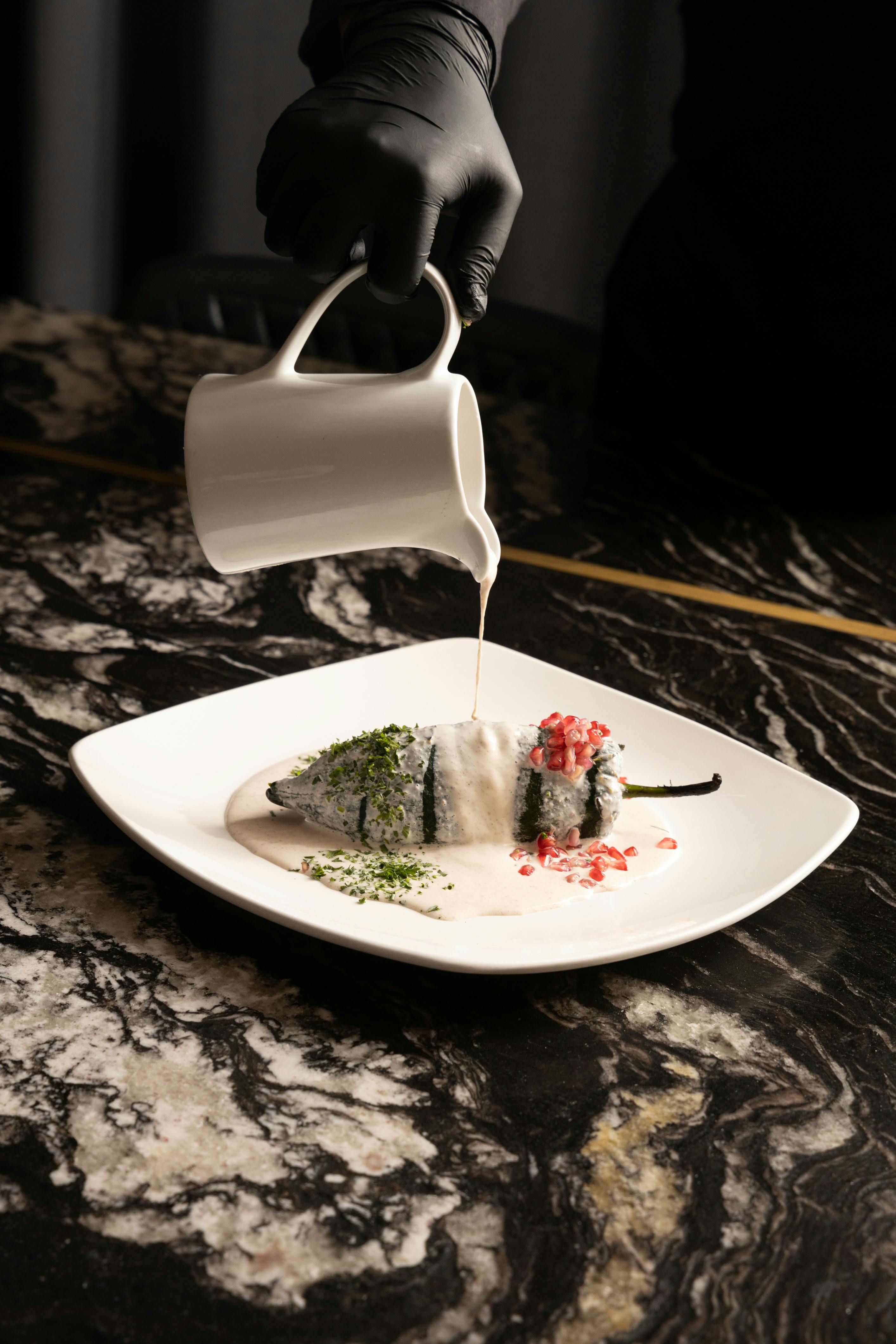 a person pouring milk on a plate with a dessert