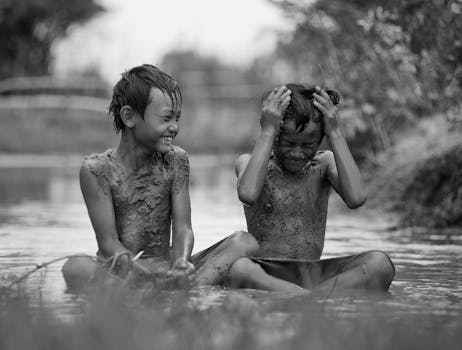 Two children enjoying playtime in muddy waters in Nha Trang, Vietnam.