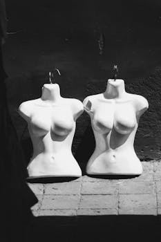Artistic black and white photo of two mannequin busts against shadowed background.