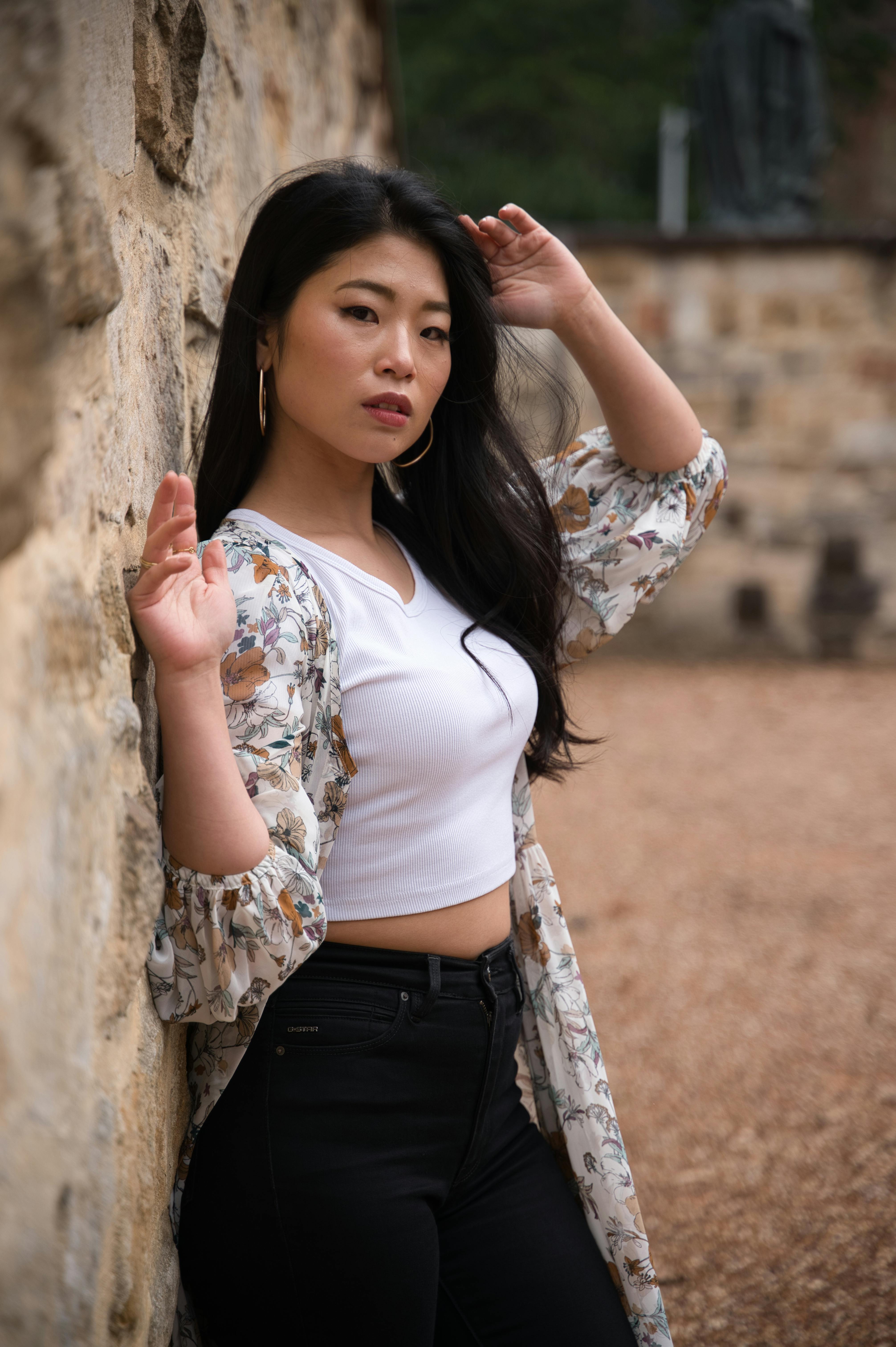 Chic young woman in trendy outfit posing against a stone wall outdoors in Sydney, Australia.