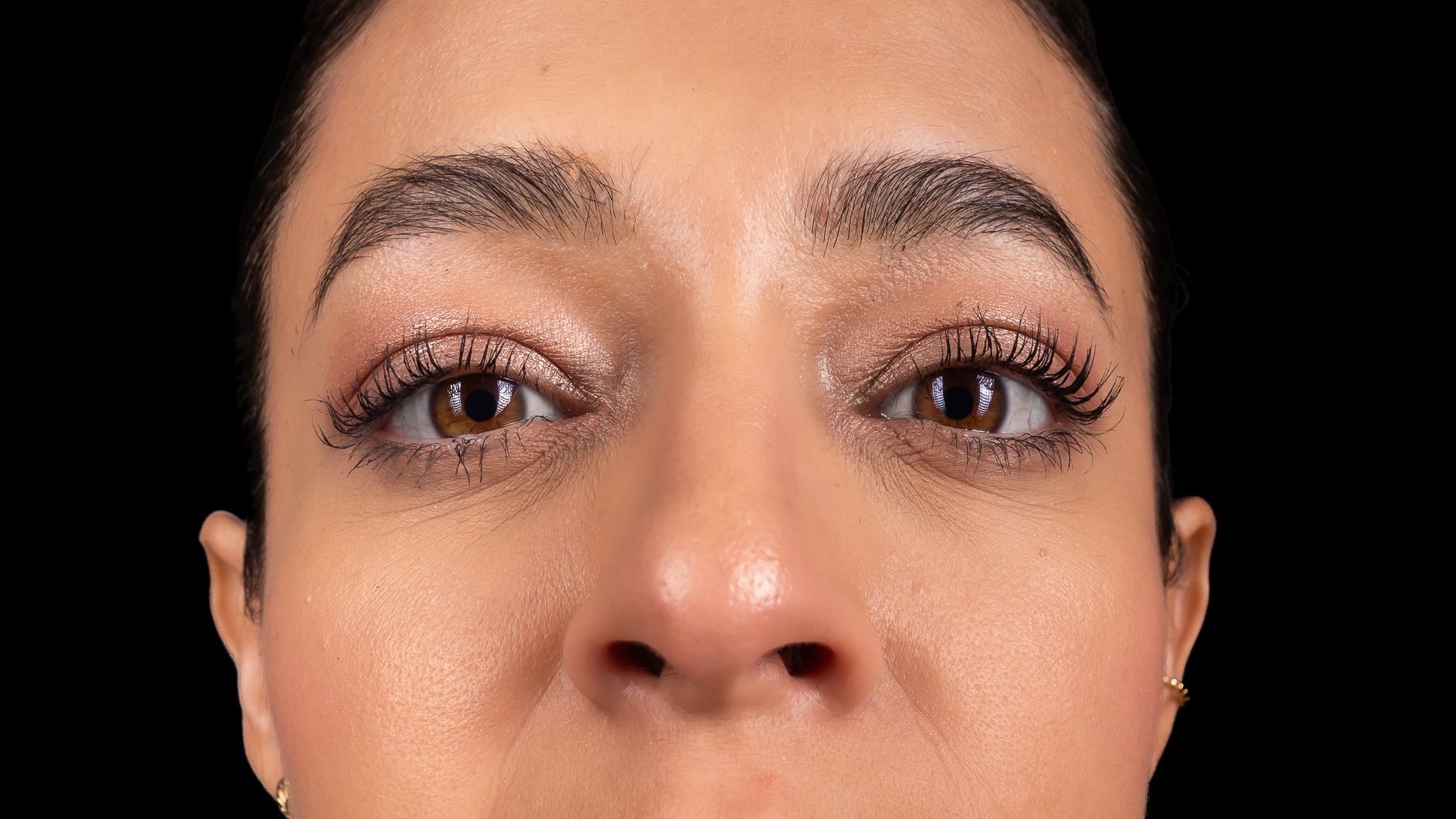 Close-up of a woman's eyes and face with elegant makeup, highlighting her natural beauty and expression.