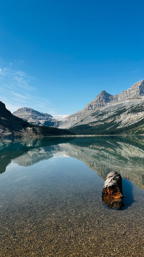Free A tranquil lake reflecting towering mountains under a clear blue sky, showcasing natural beauty. Stock Photo
