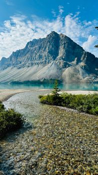 A breathtaking view of a rocky mountain and pristine lake under a clear blue sky.