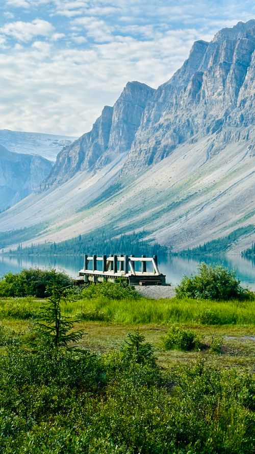 Free Serene mountain landscape featuring a clear lake and observation platform under a blue sky. Stock Photo