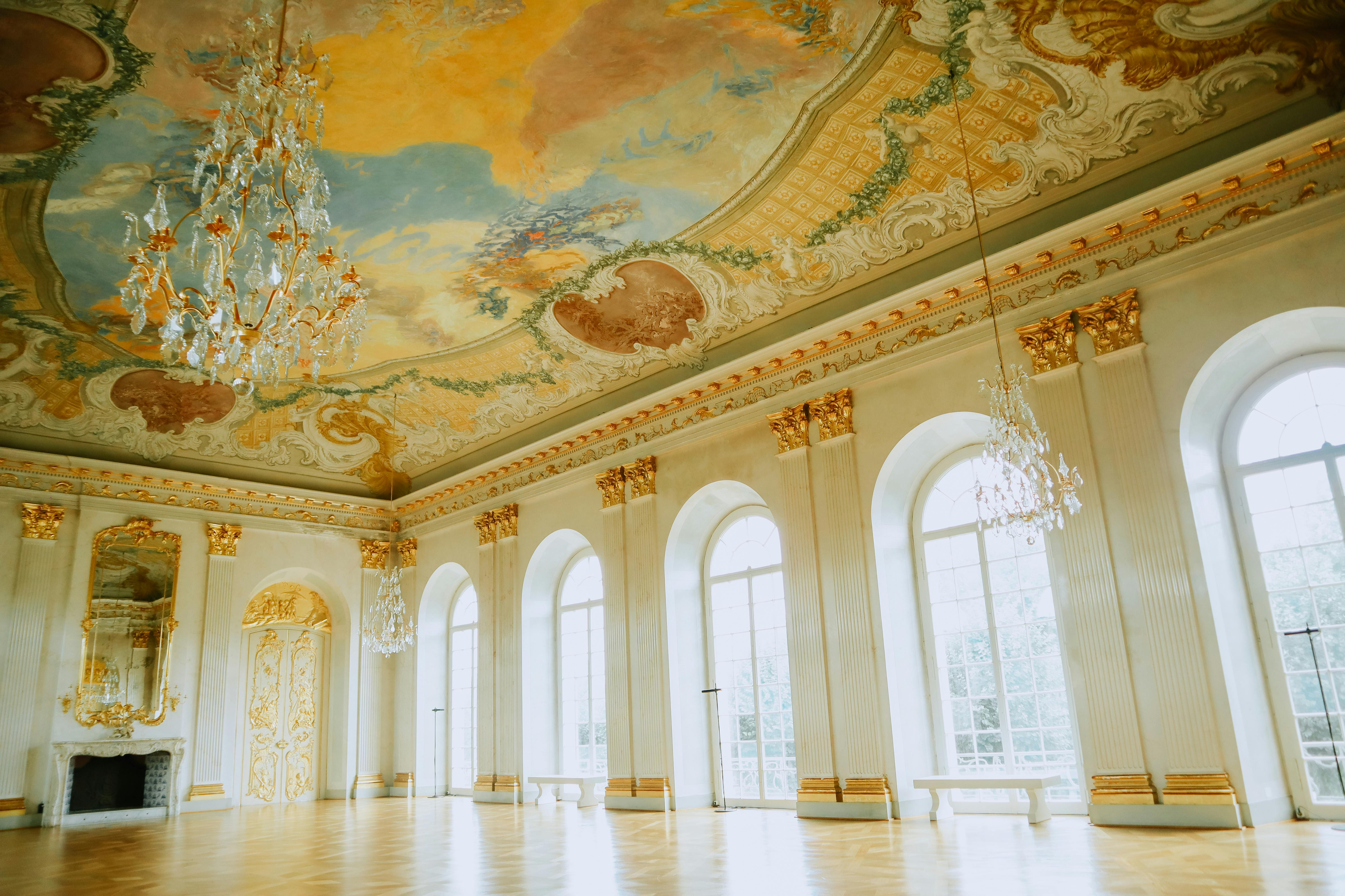 Elegant ballroom featuring a grand chandelier and intricately painted ceiling, exemplifying opulent 