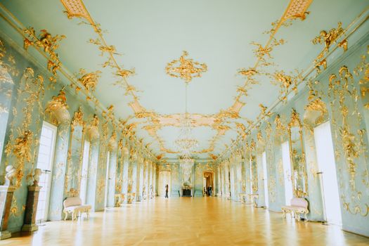 Luxurious Baroque-style room with intricate gold detailing and elegant chandeliers.