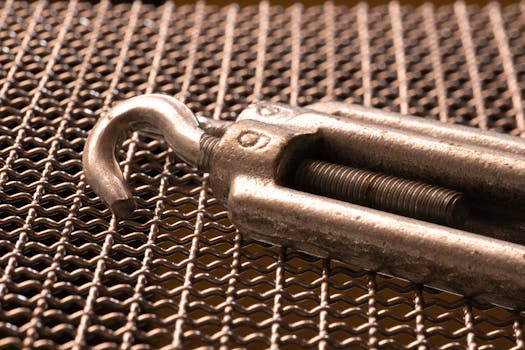 Detailed shot of a metal hook on a grid mesh, showcasing texture and industrial design.