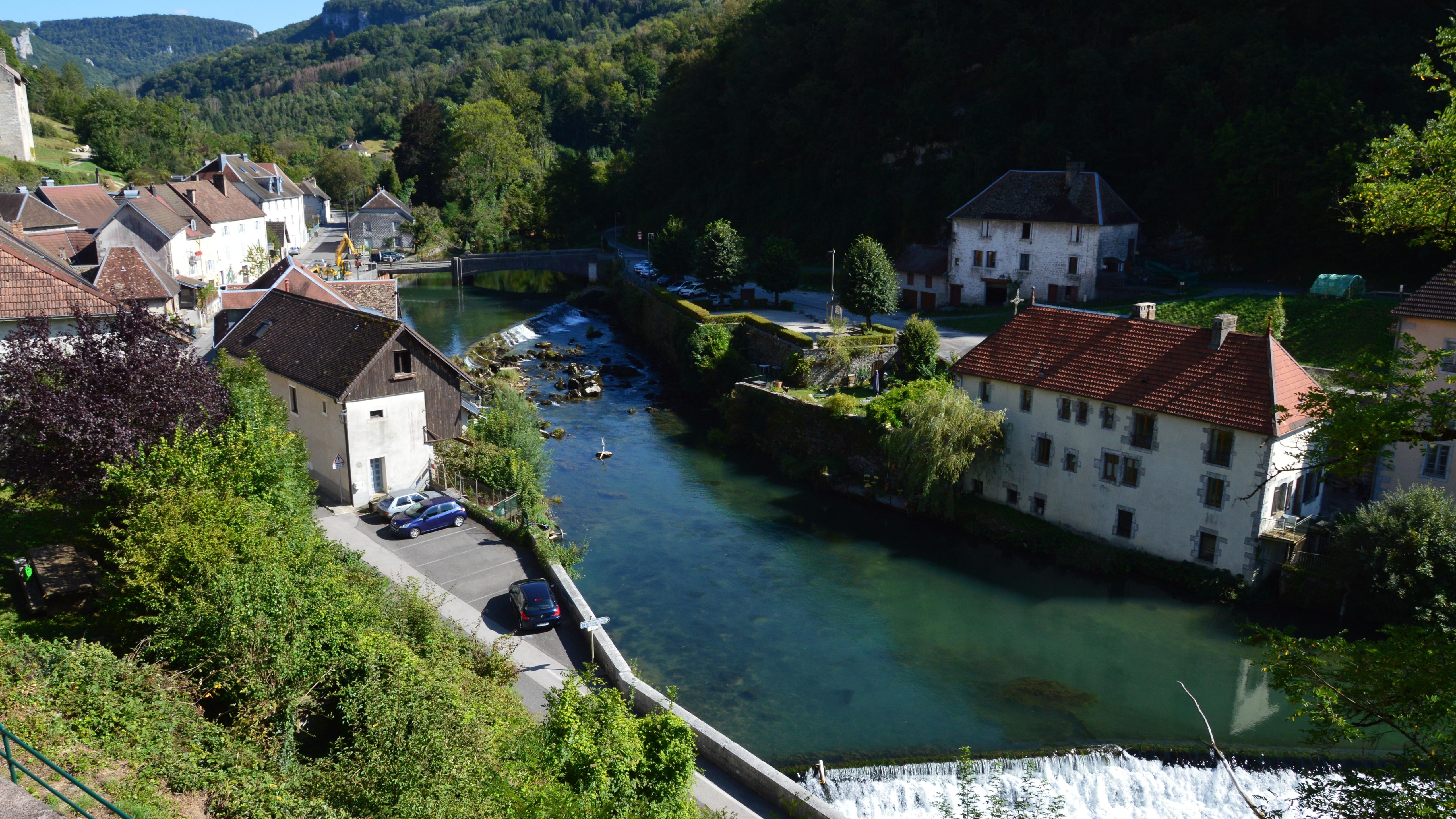 River view with quaint houses and lush greenery in a French village.