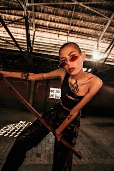 一位时尚的纹身女子戴着太阳镜，穿着休闲服，在室内自信地摆着姿势