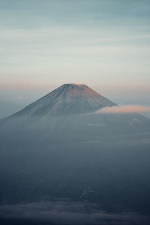 Free Tranquil scene of a mountain peak enveloped in mist during dawn, creating a mystical atmosphere. Stock Photo