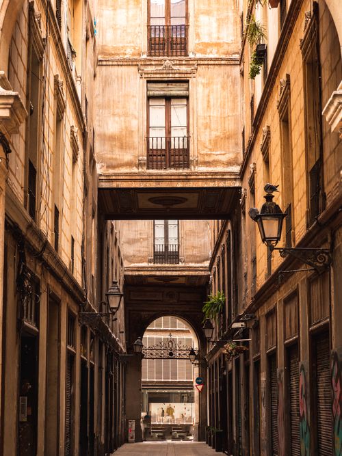 Free A narrow historic European alleyway featuring arches and rustic apartment buildings. Stock Photo