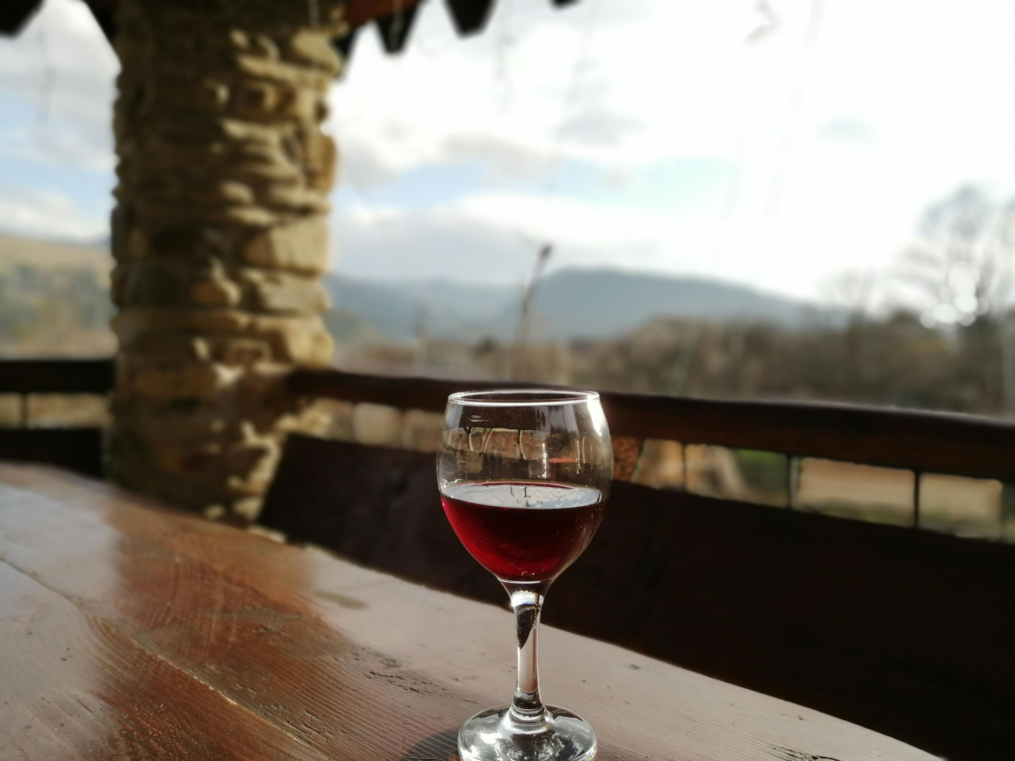 A peaceful outdoor setting with a glass of red wine on a wooden table.