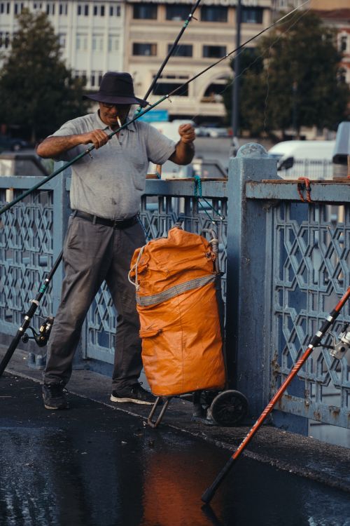 Free A fisherman prepares his fishing rod on a bridge in İstanbul, Türkiye. Stock Photo