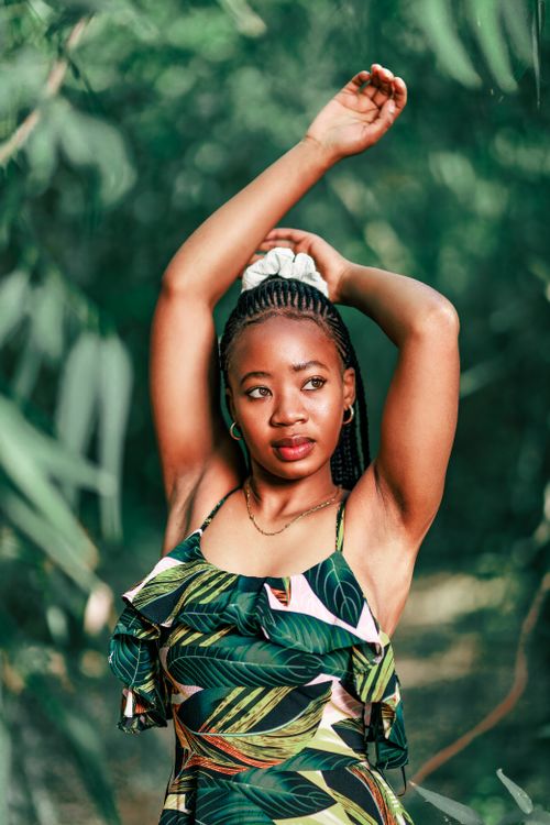 Free Stylish woman in nature, wearing a tropical dress, striking a graceful pose outdoors. Stock Photo