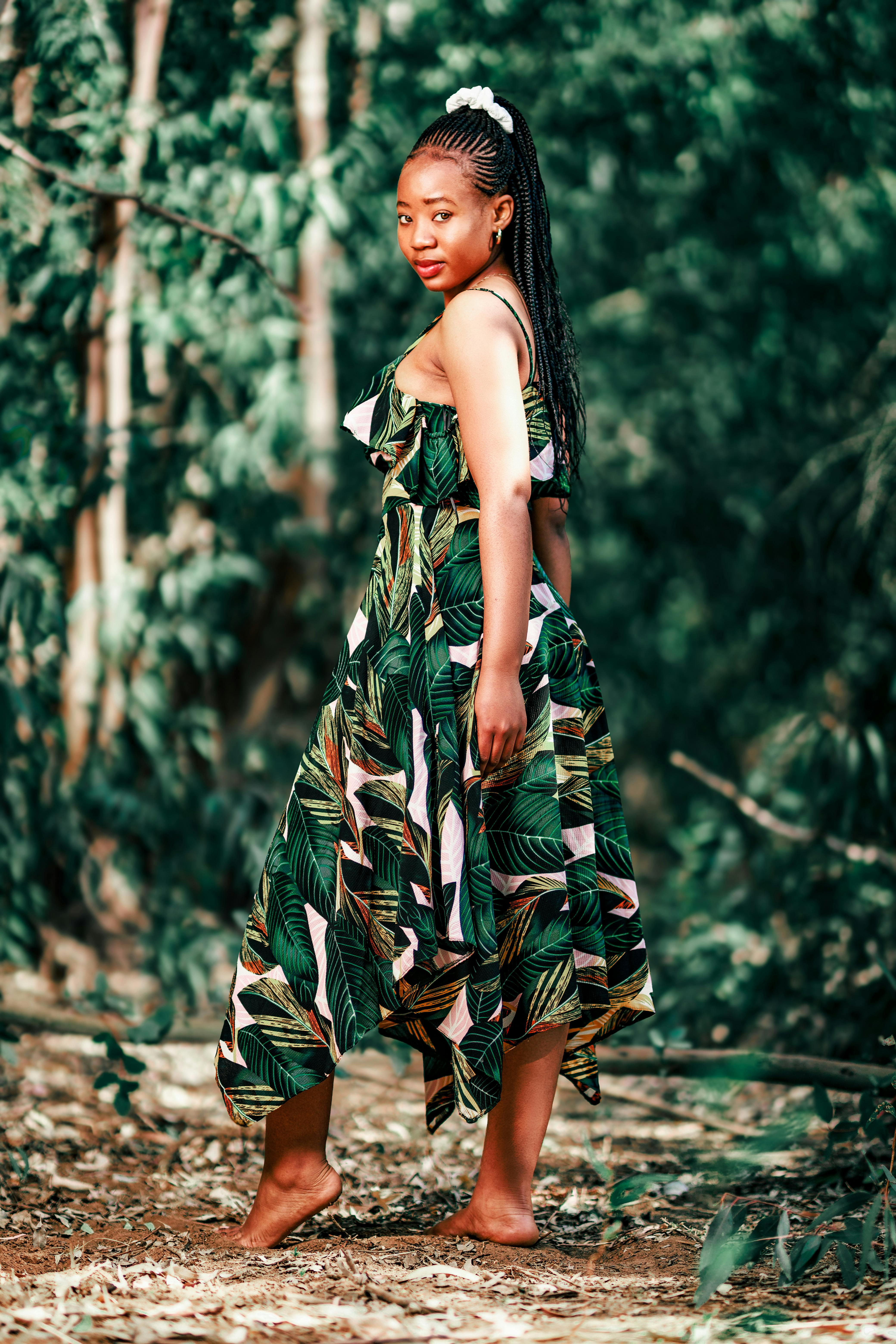 a woman in an african print dress standing in the woods