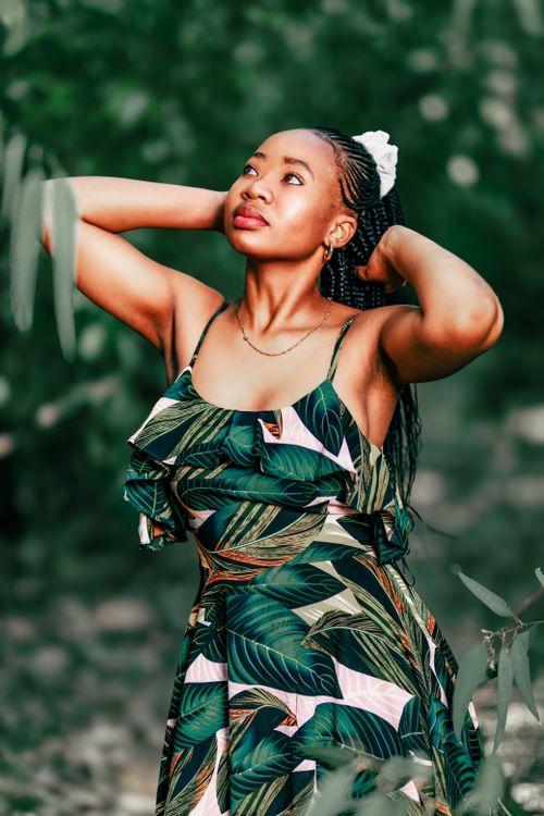 Free Charming woman in a tropical dress poses gracefully outdoors, exuding elegance. Stock Photo