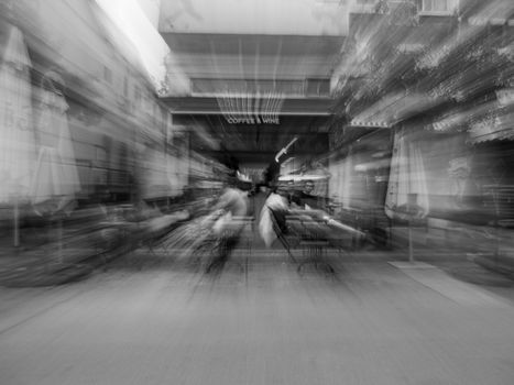 Monochrome image with zoom blur effect at a bustling coffee bar terrace.