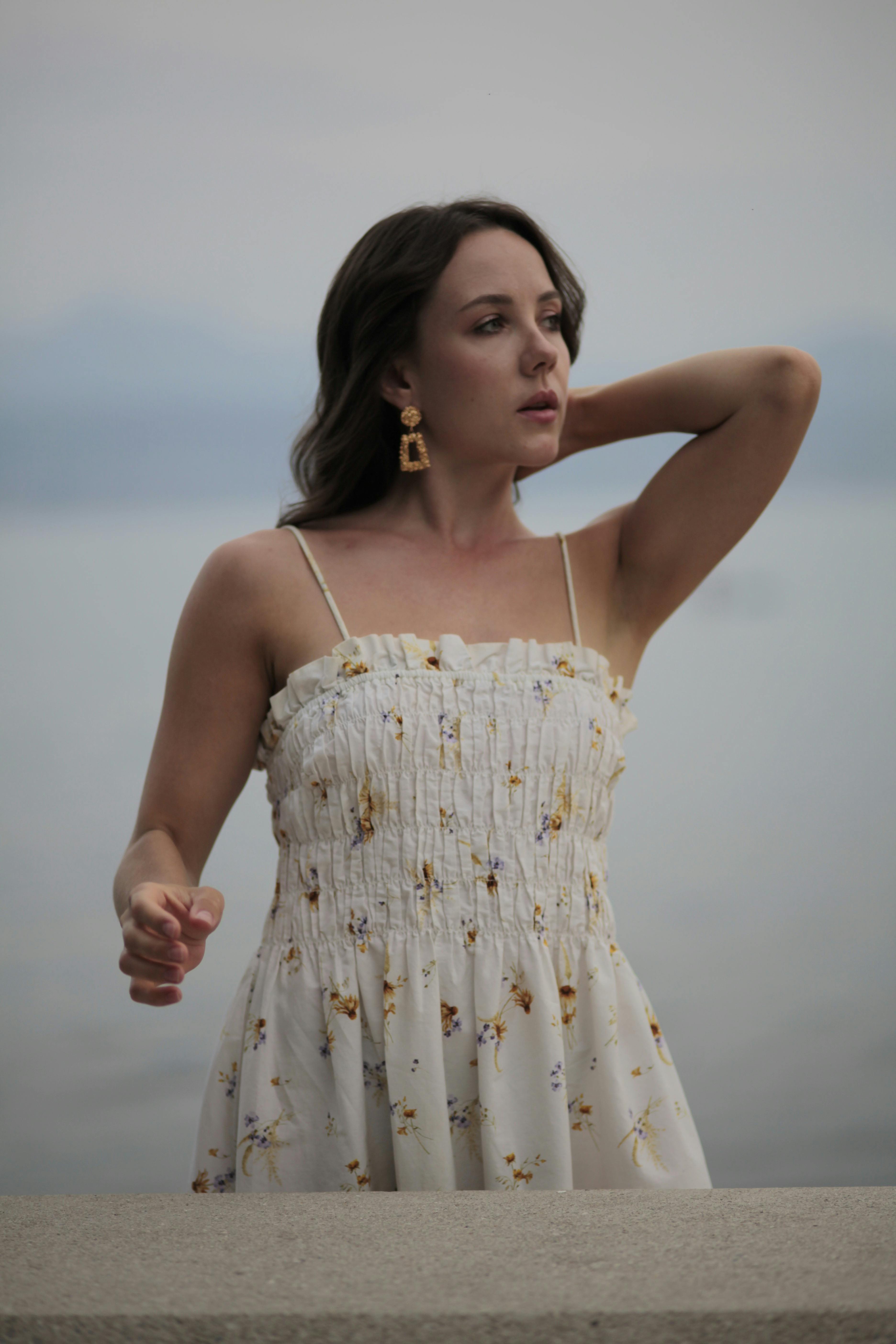 a woman in a white dress standing near the water