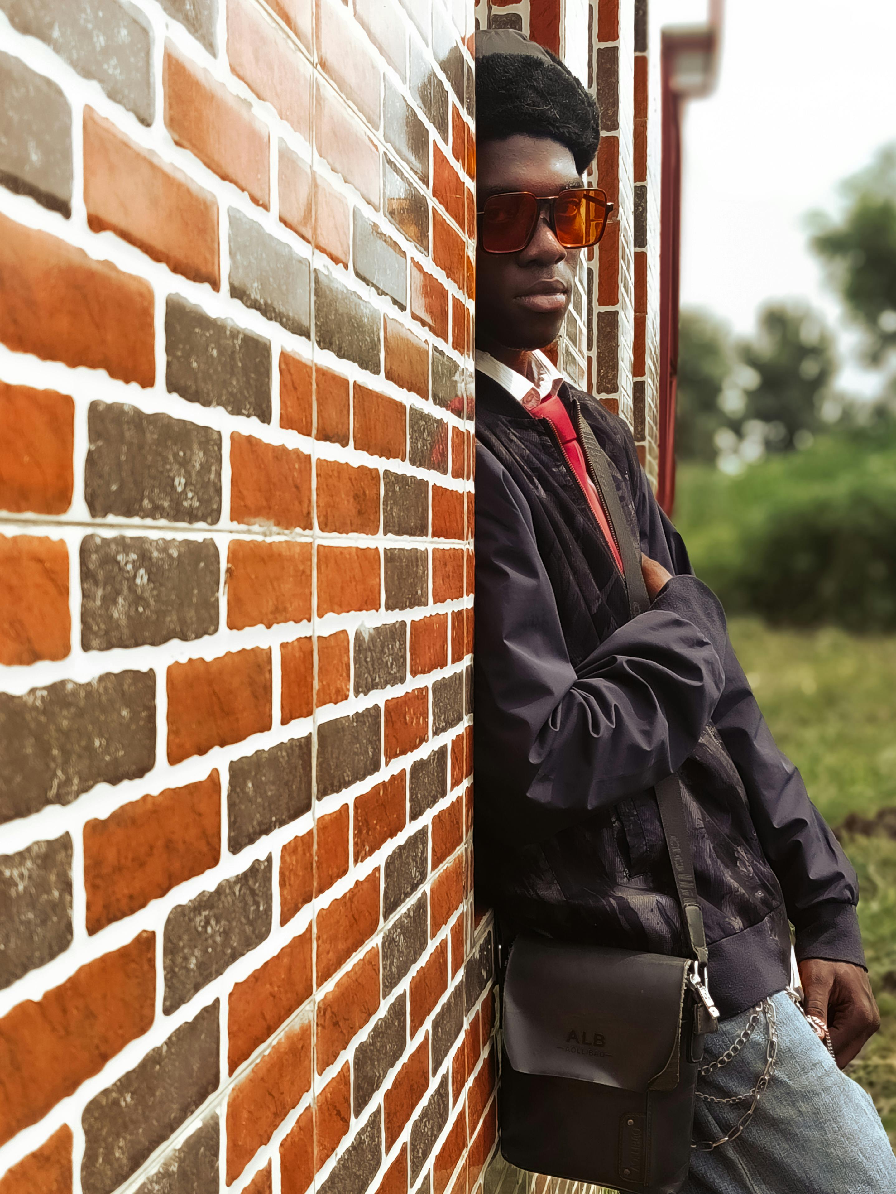 a man leaning against a brick wall with sunglasses