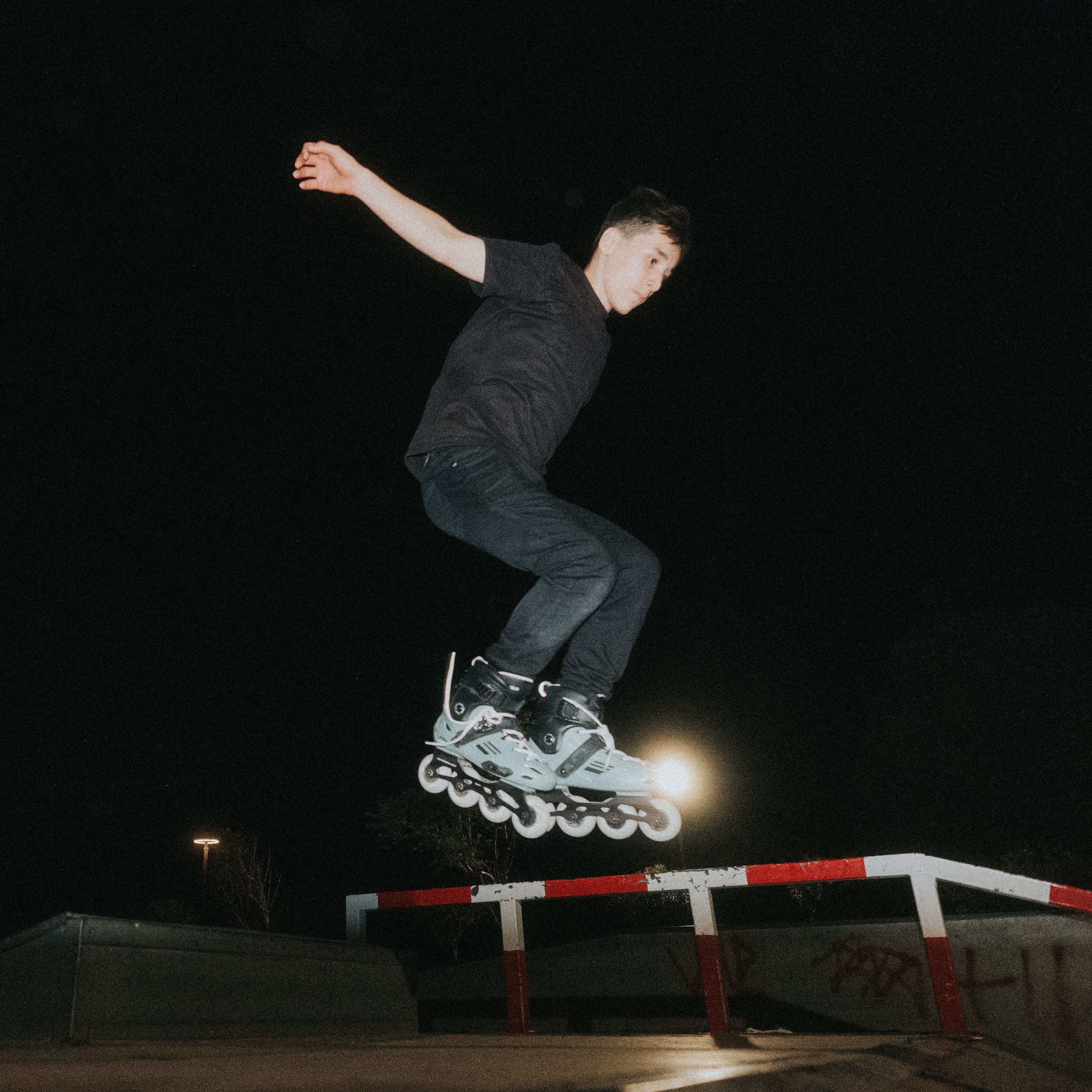 A young adult performs an impressive skateboarding jump at night in Antalya.