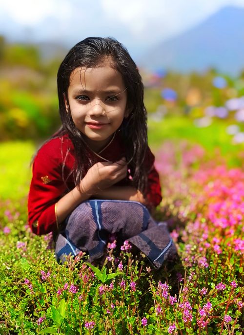 Free A child enjoying a sunny day in a colorful flower garden, exuding joy and warmth. Stock Photo