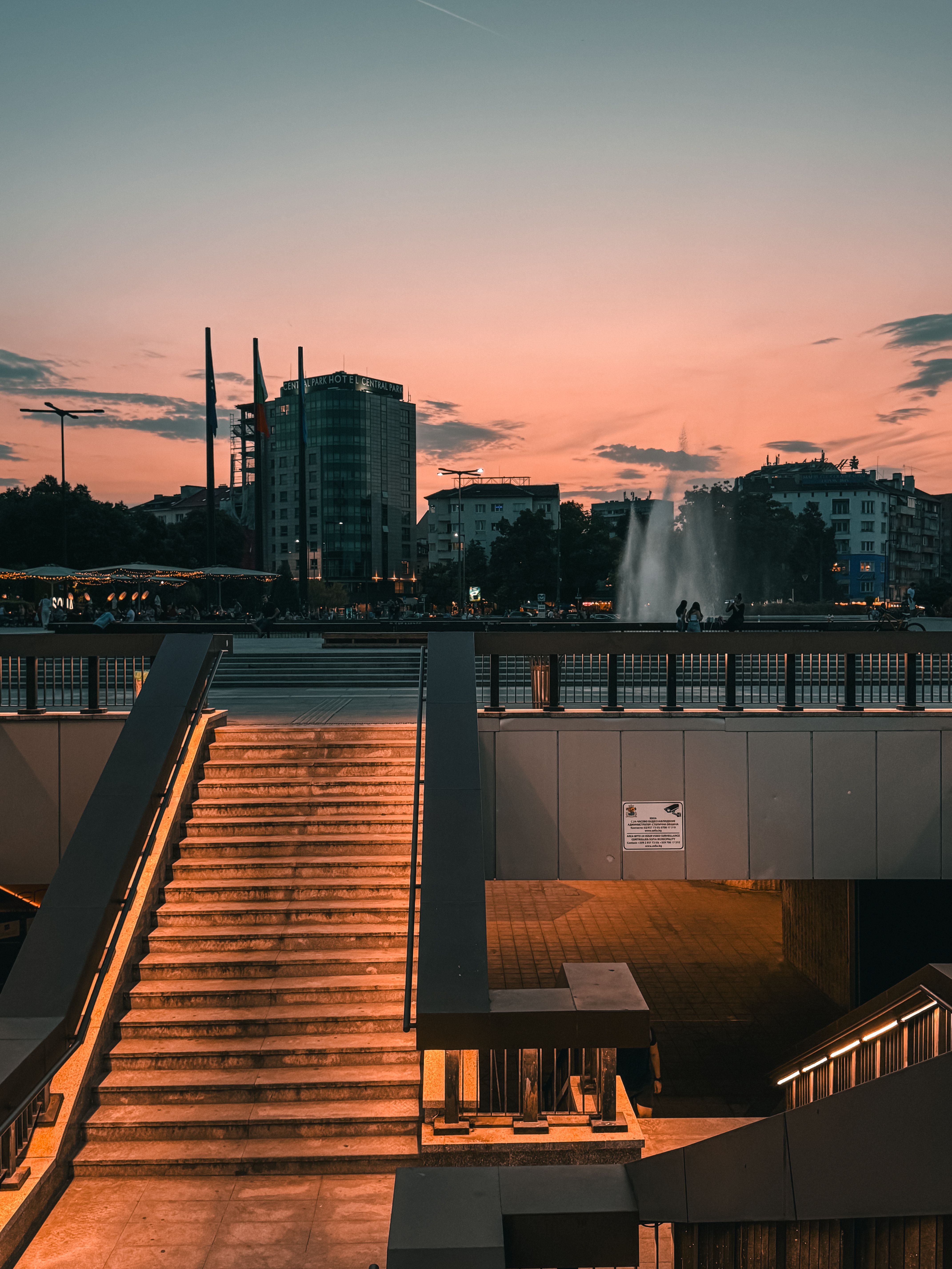 Scenic view of Sofia's skyline during sunset, featuring an illuminated bridge and city fountain.