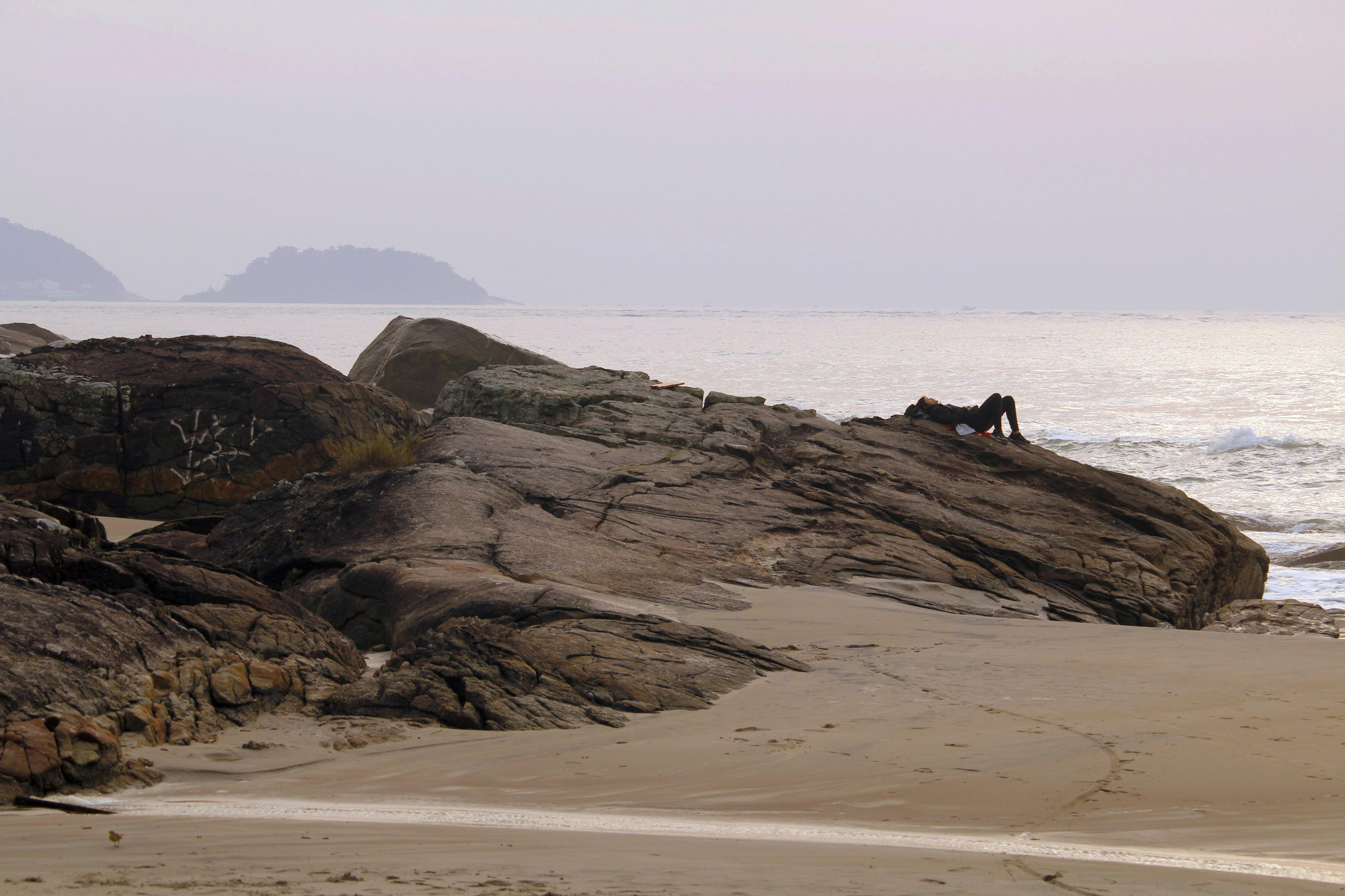 a person sitting on a rock at the beach