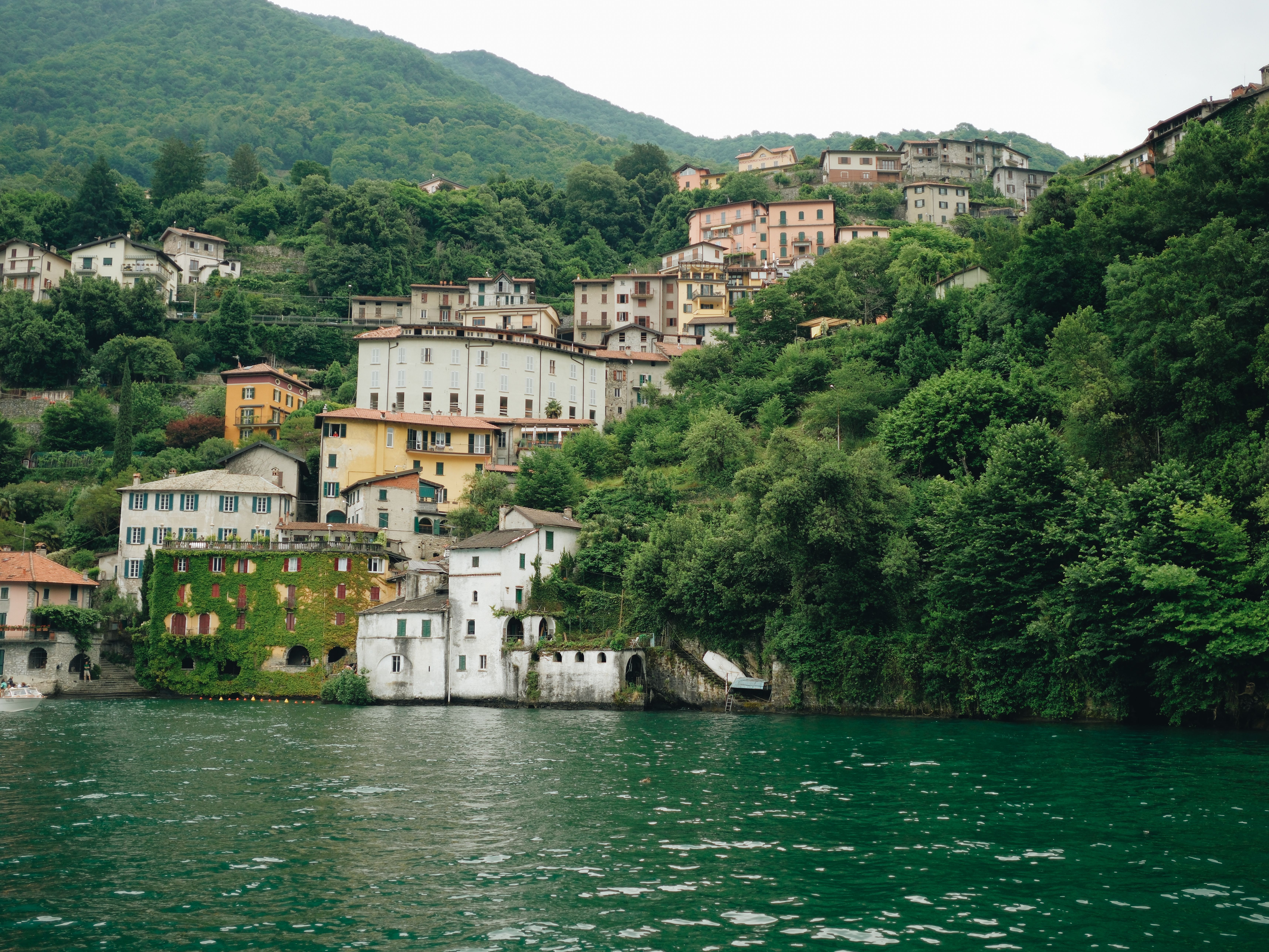 Charming hillside village with colorful houses by Lake Como, surrounded by lush greenery.