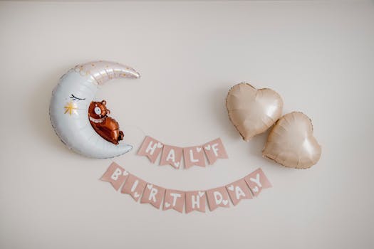 Decorative setup for a half birthday featuring balloons and a bear on a crescent moon.