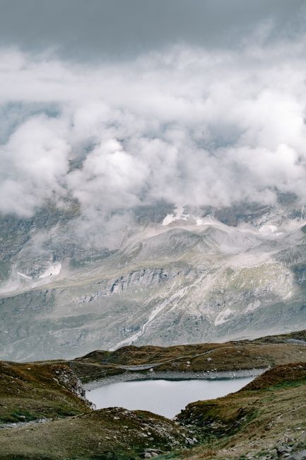 Breathtaking view of a mountain lake surrounded by clouds and rugged peaks.
