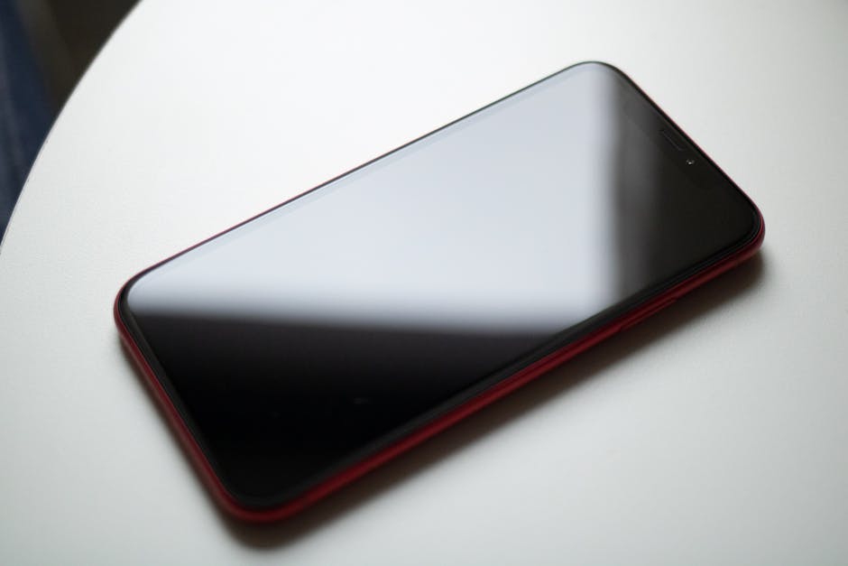 Synthesia vs HeyGen: AI Avatar Video ROI (2026) A sleek red smartphone placed on a white table showcasing modern digital technology.