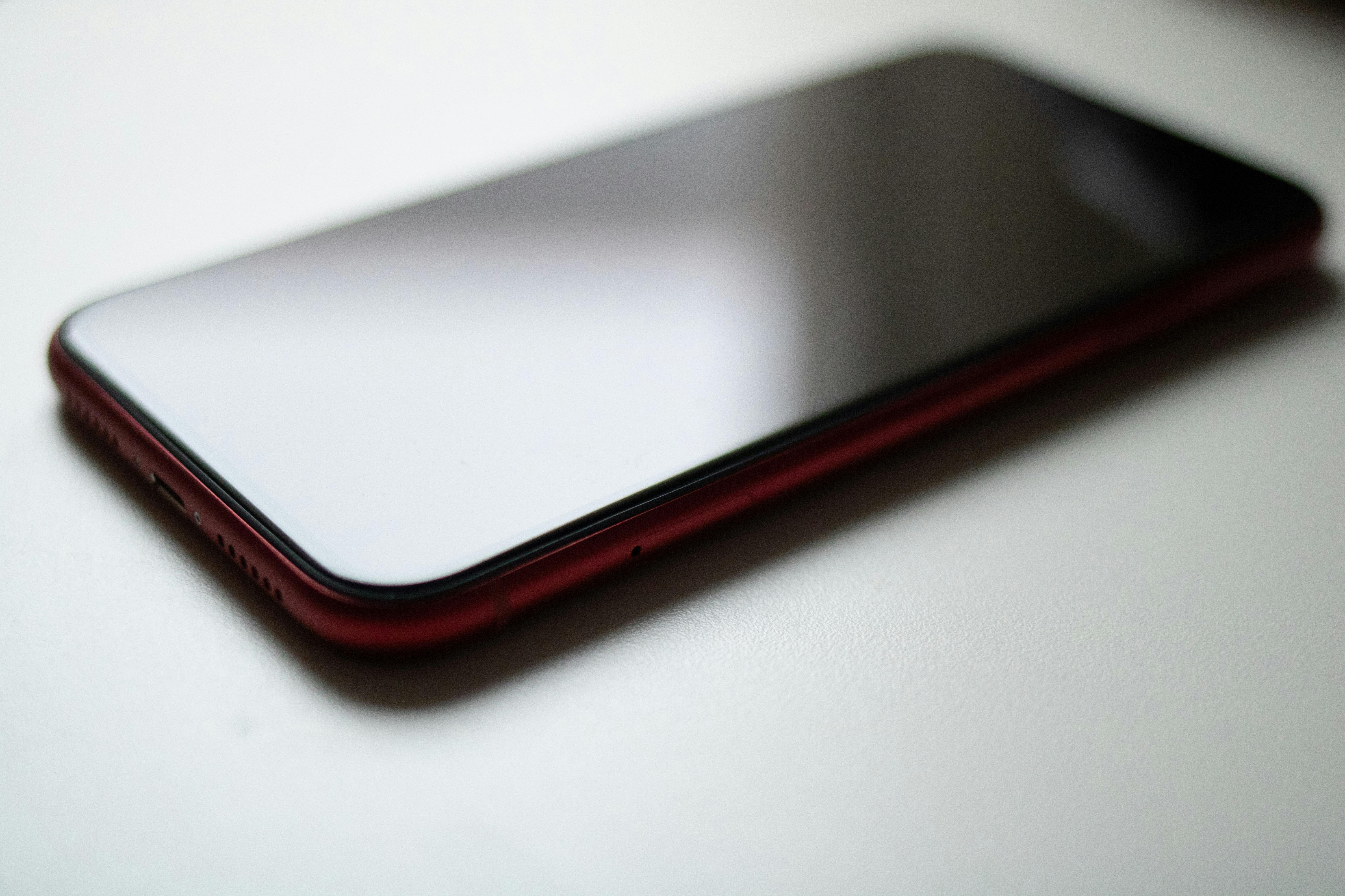 red smartphone on white surface