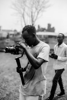 Young filmmakers using a camera gimbal for outdoor shooting. Capturing dynamic shots, teamwork in filmmaking.