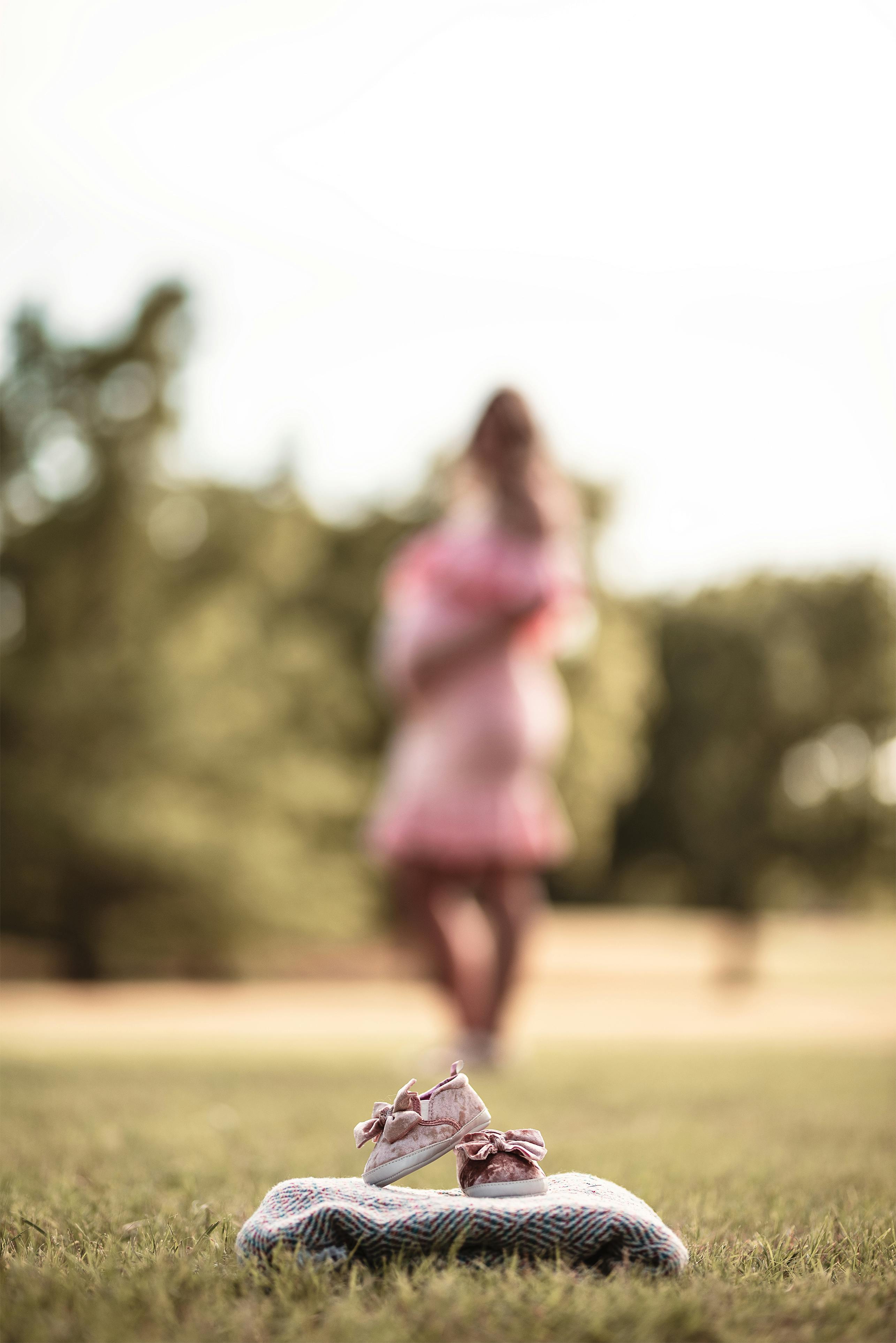 pair of baby s pink shoe on gray textile macro photography