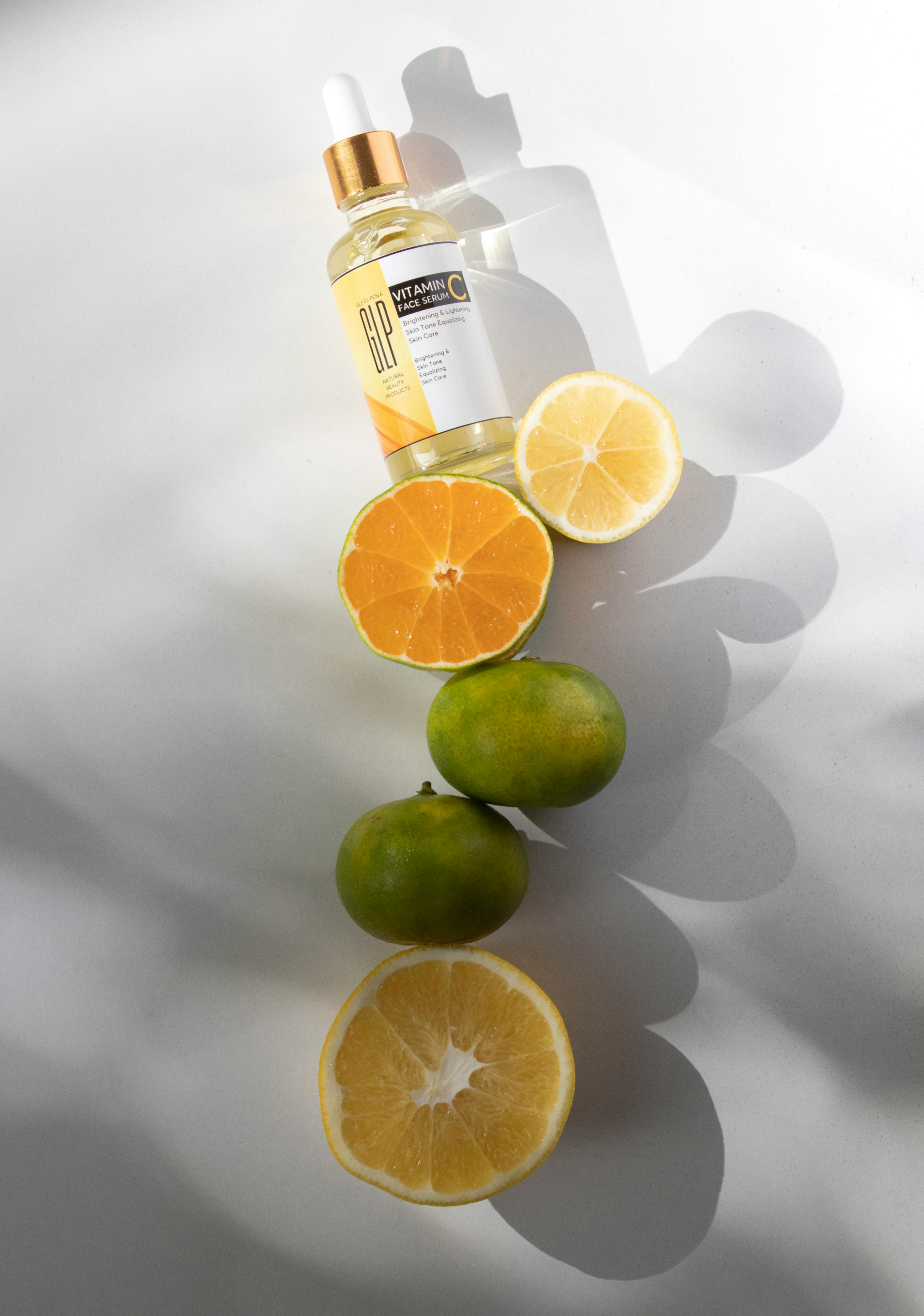 Free Vitamin C serum and sliced citrus fruits in bright minimalistic studio setup. Stock Photo