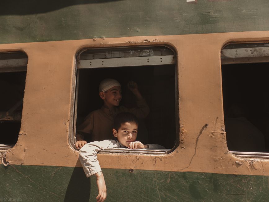 Two boys peering out of a train window, capturing a moment of travel and curiosity.