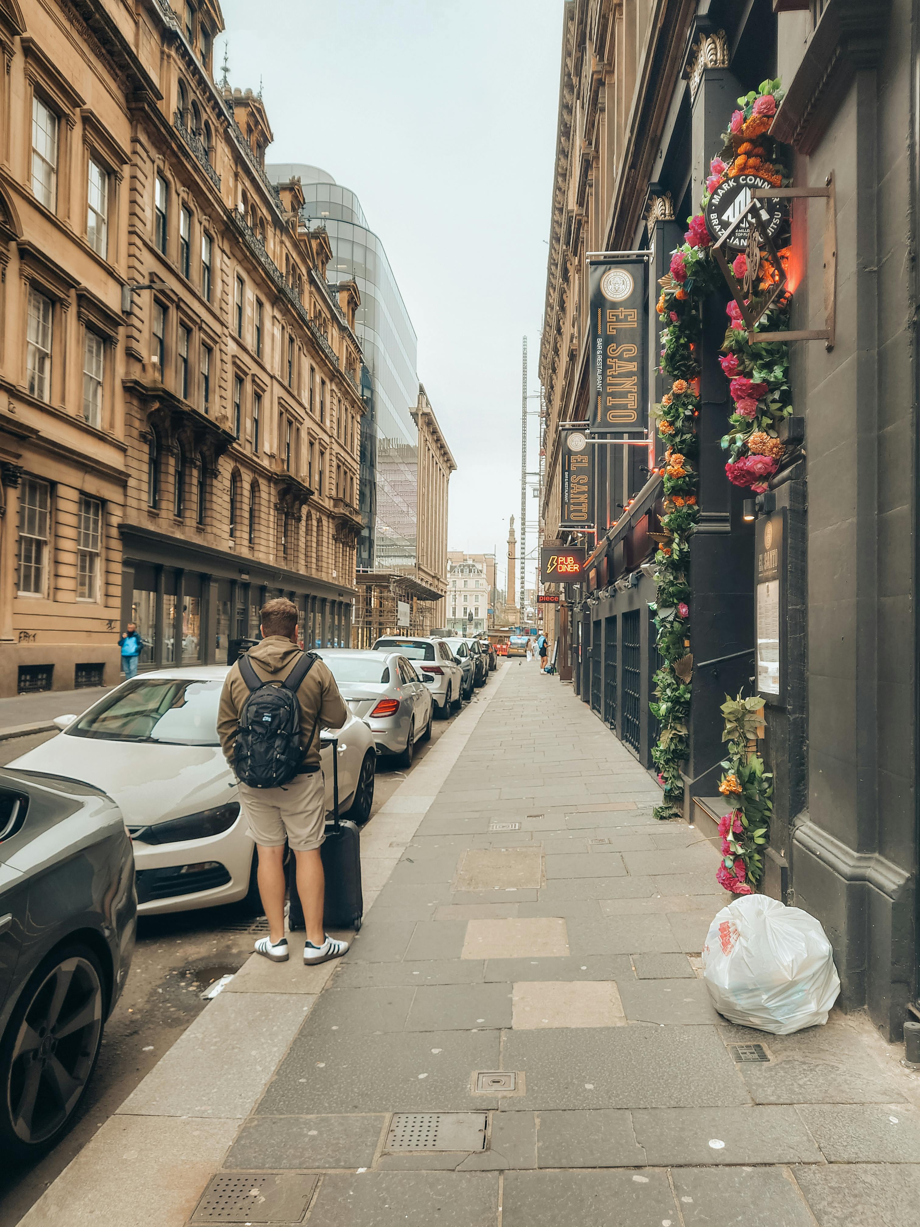 a person walking down a street with flowers on the side