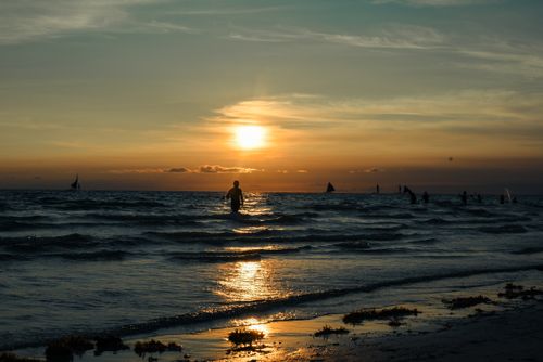 Free Silhouetted figure at sunset with sailboats and gentle waves in Kalibo, Philippines. Stock Photo