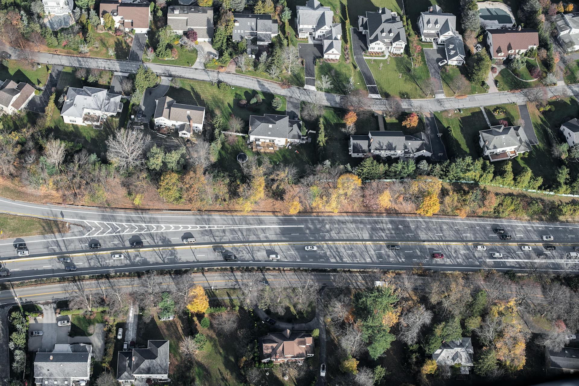 Aerial view of a suburban neighborhood with adjacent highway, showcasing urban planning and transportation systems.