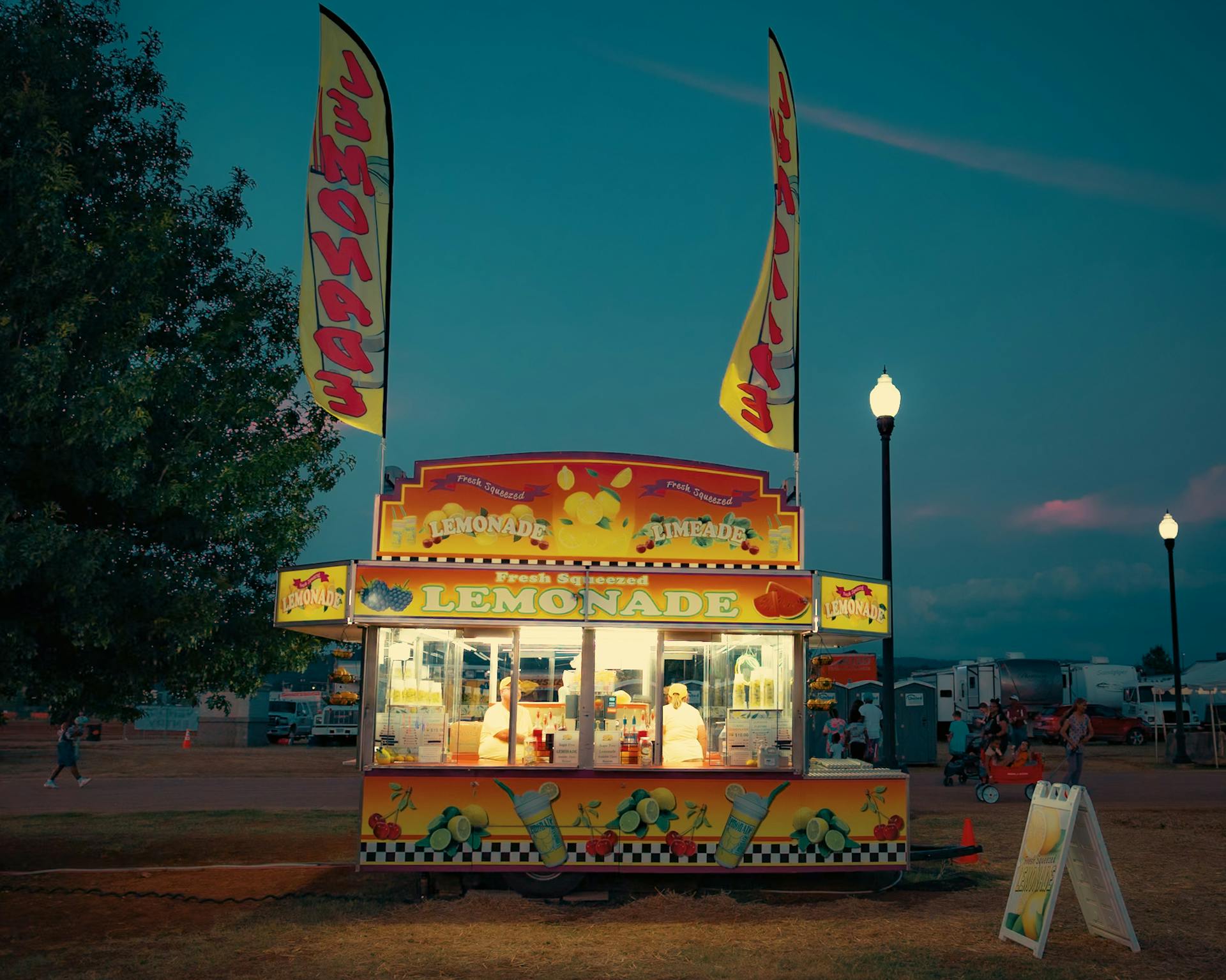 Vibrant lemonade stand at a festive outdoor setting during a colorful evening.